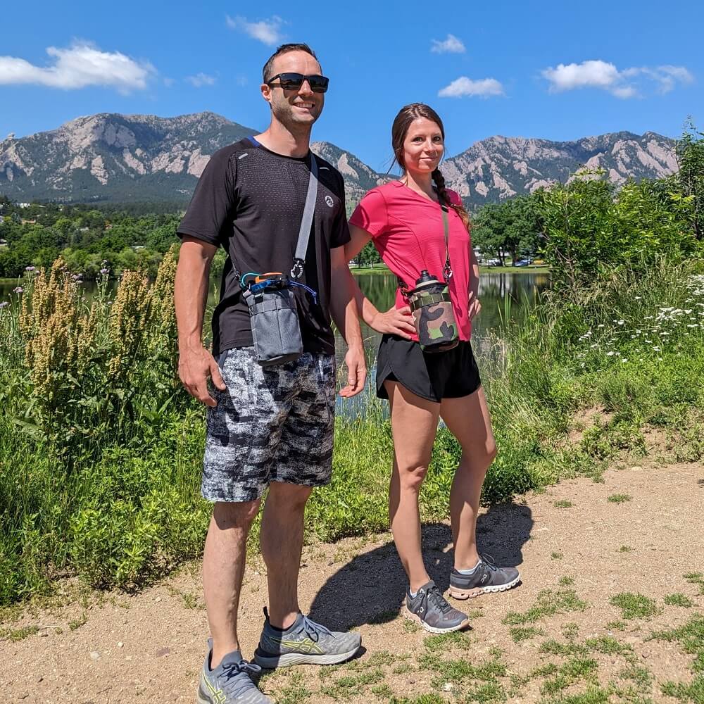 Couple wearing water bottle slings with mountain background. 