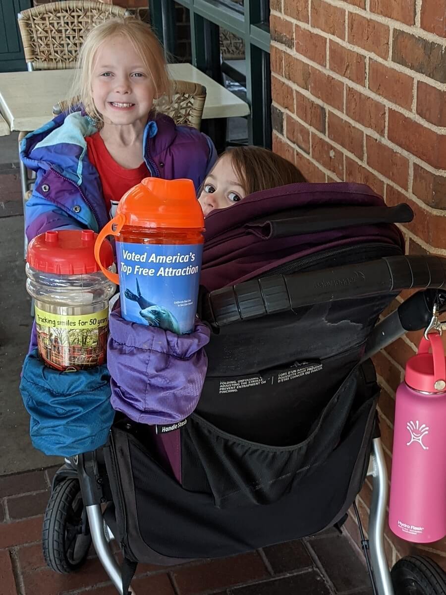kids in stroller with cup holders carrying zoo cups