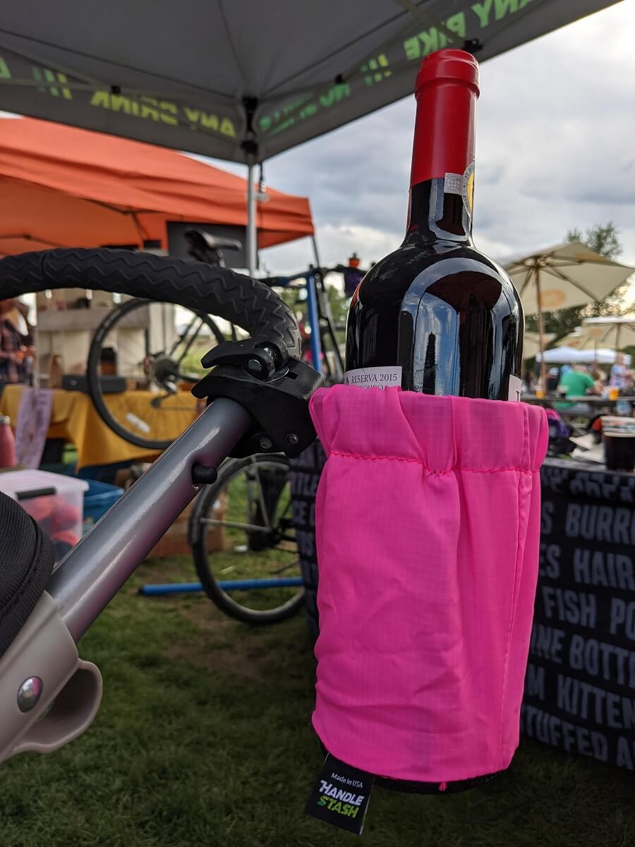 wine bottle on stroller handle in pink cup holder