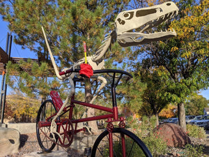 Dinosaur on bike carrying beef jerky