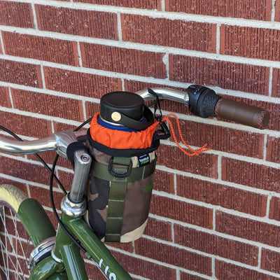 Camouflage bike stem bag with orange liner on bicycle handlebars. 