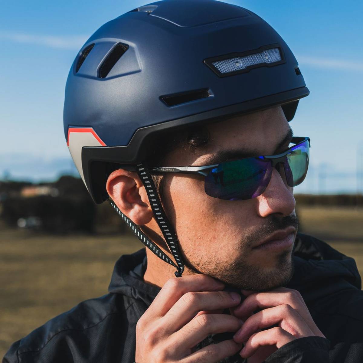 man clipping fidlock strap on xnito ebike helmet and looking really serious