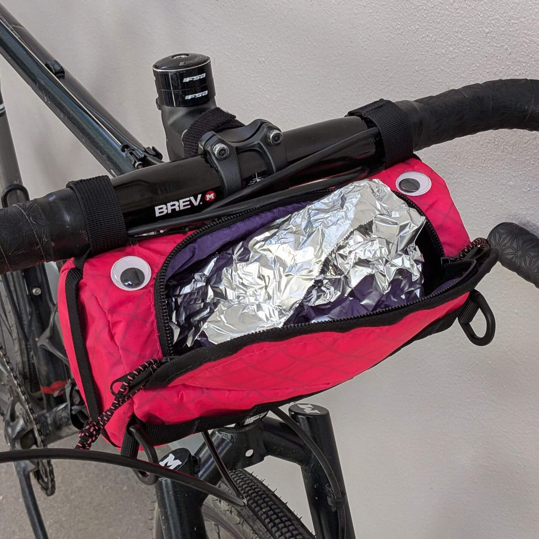 pink ecopak handlebar bag with googly eyes and a burrito sticking out