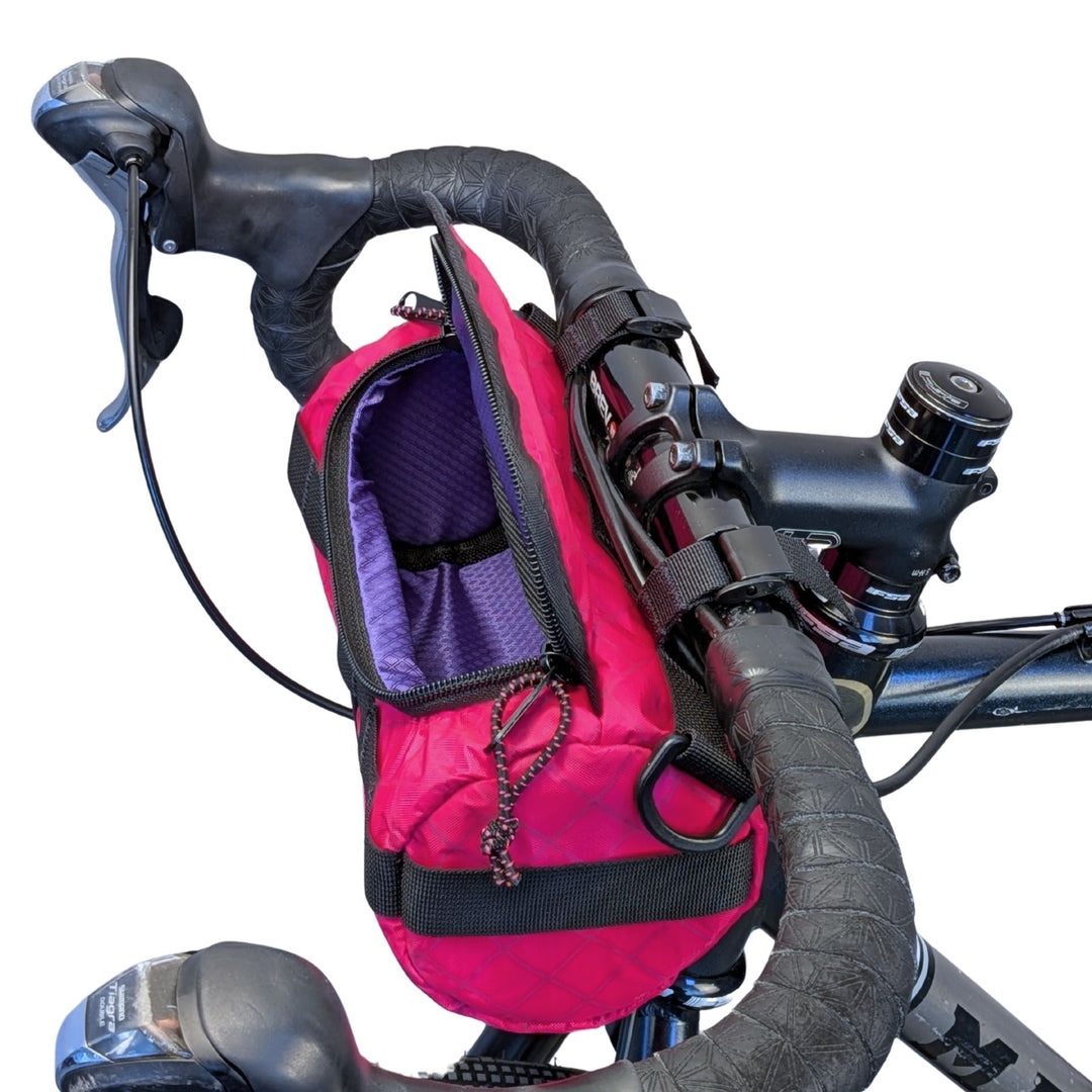 Pink ECOPAK bicycle bag with wide opening and purple liner attached to a bike handlebar on a white background