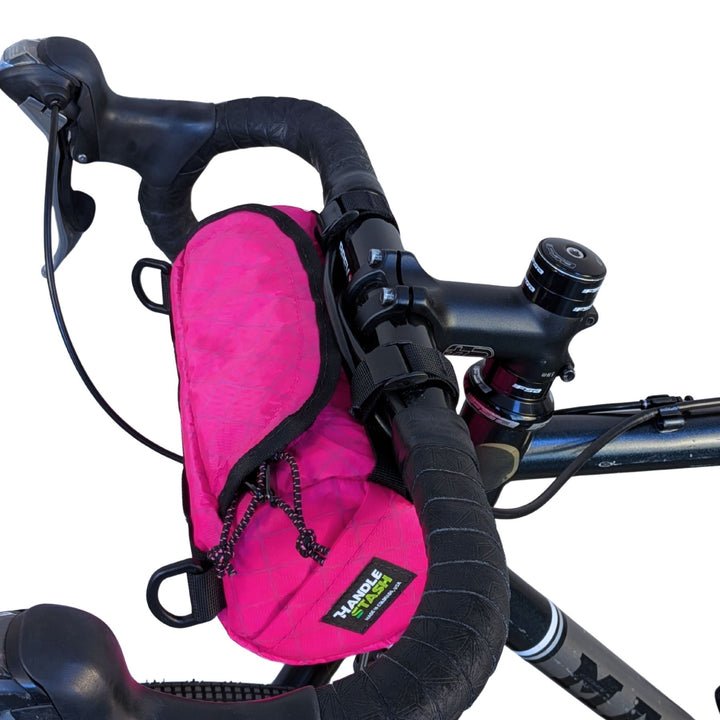 Pink ecopak bicycle handlebar bag attached to a bike with a white background